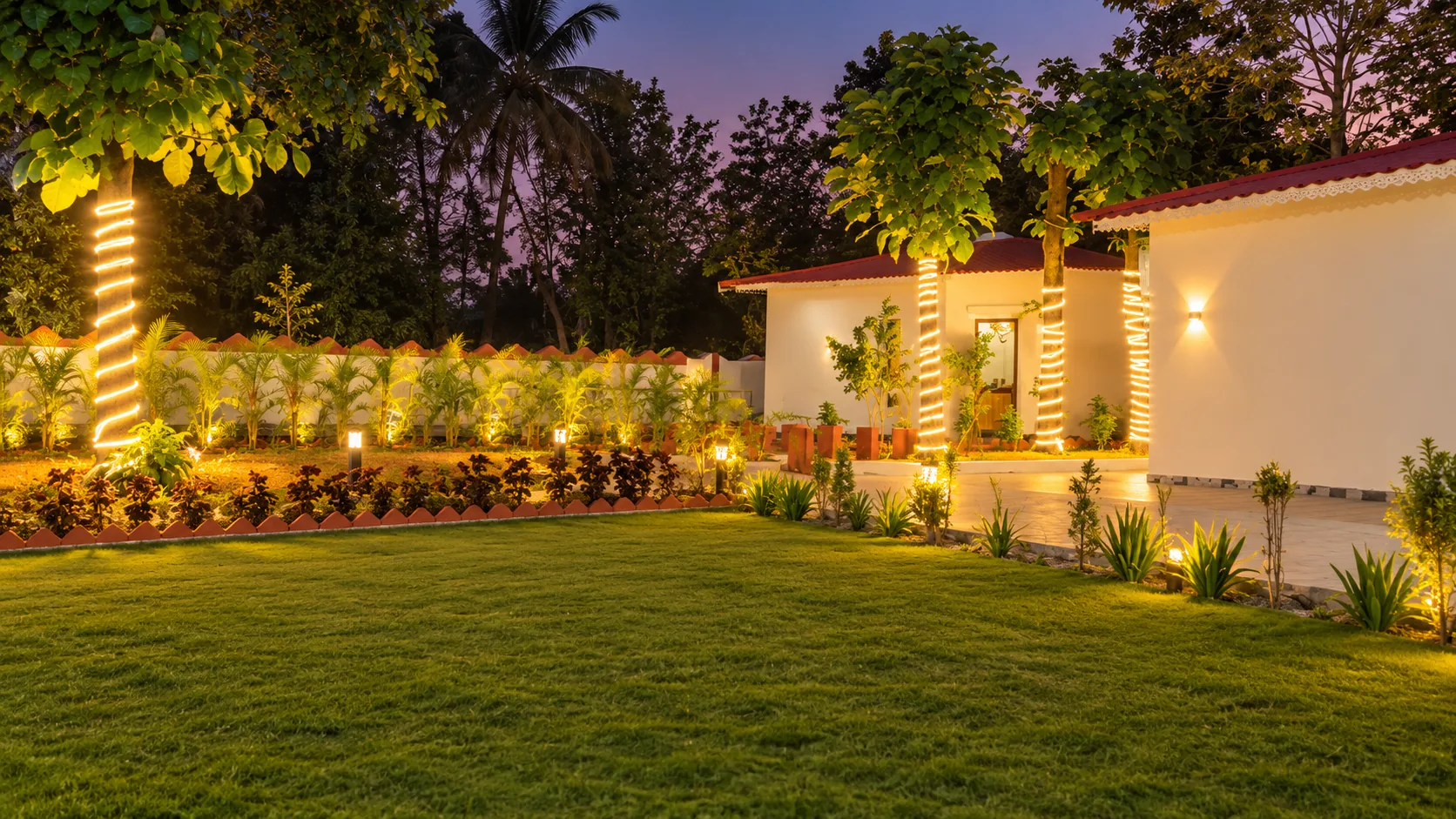 Lawn and farmhouse with evening garden lights